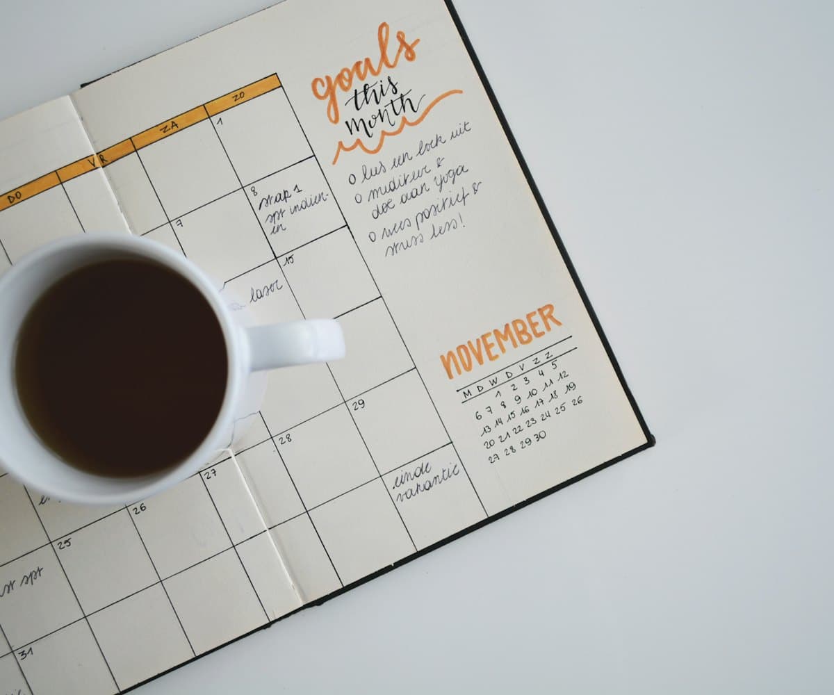 A monthly planner open at a page of goals, with a cup of coffee beside it